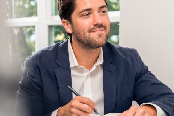 man in black suit jacket holding pen